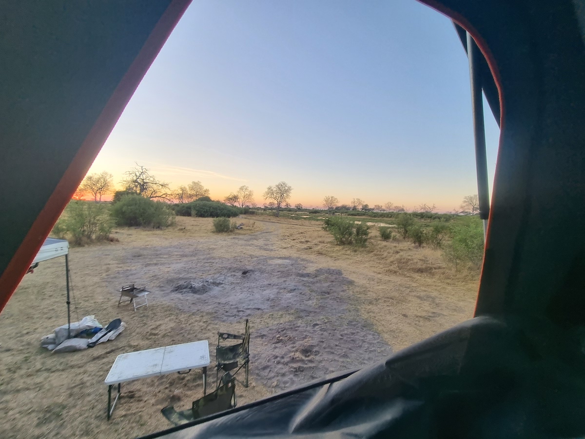 Looking out from a rooftop tent over camp chairs and dry grassland