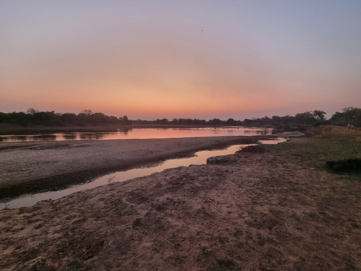A still river reflecting peach and orange dusk light