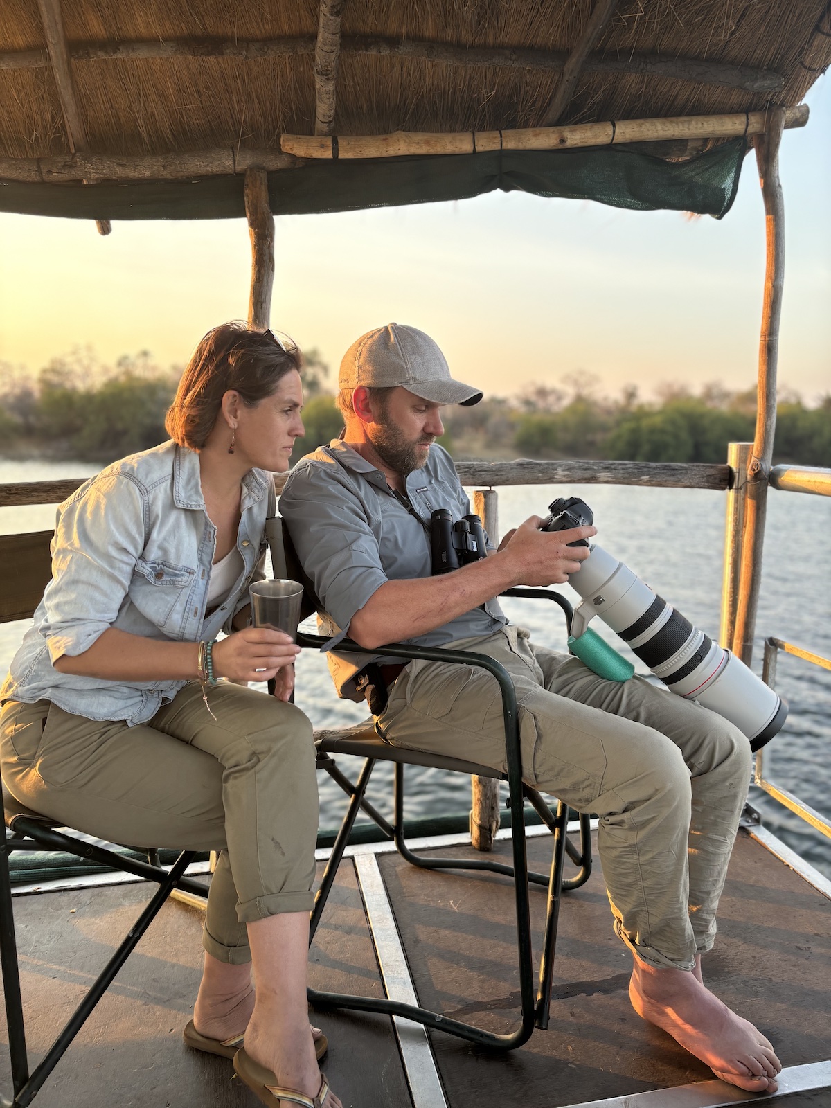 Reviewing photographs on a boat at sunset, with a telephoto lens and binoculars at hand