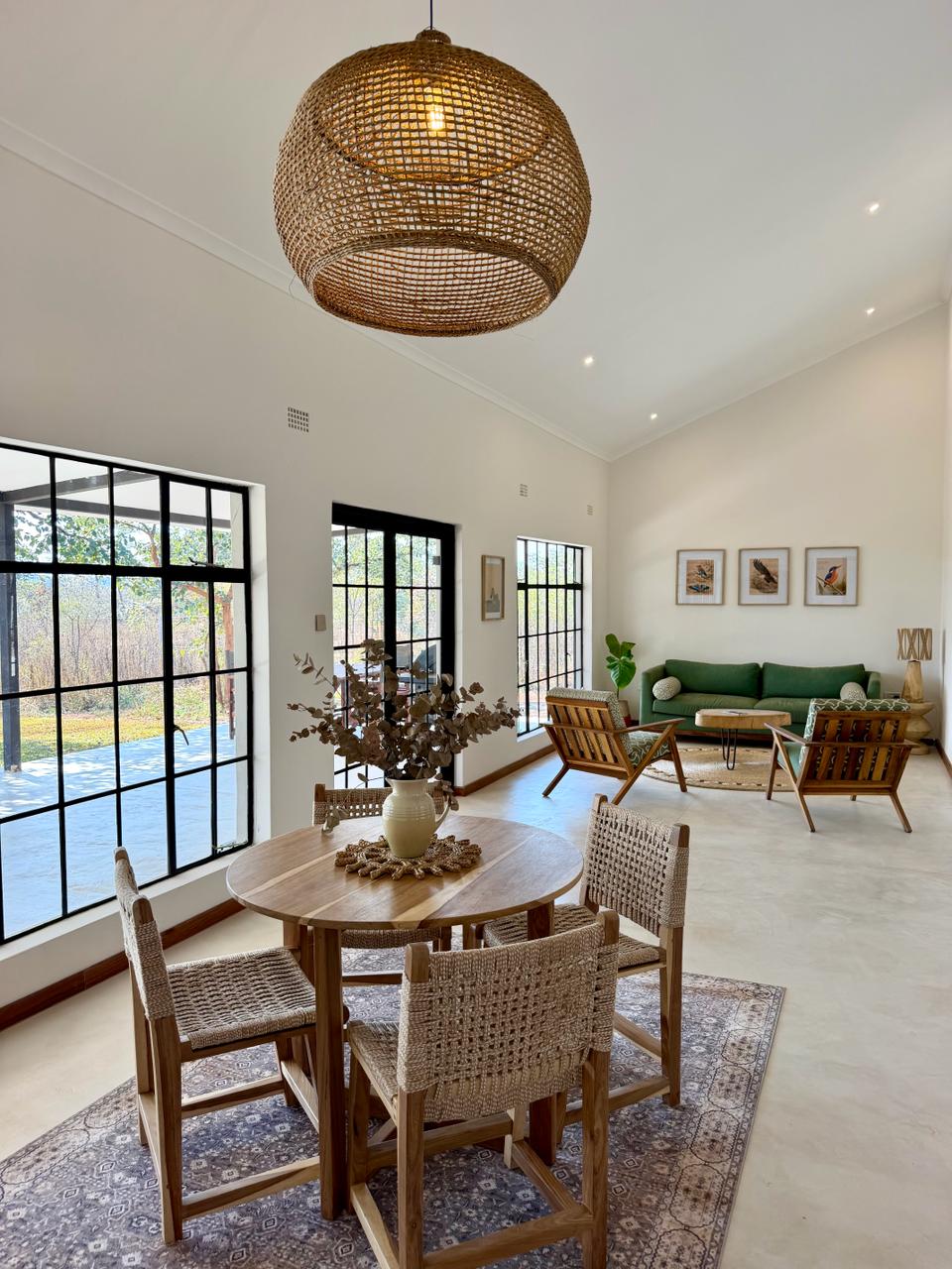 Open-plan living and dining, looking through black-framed windows to the garden