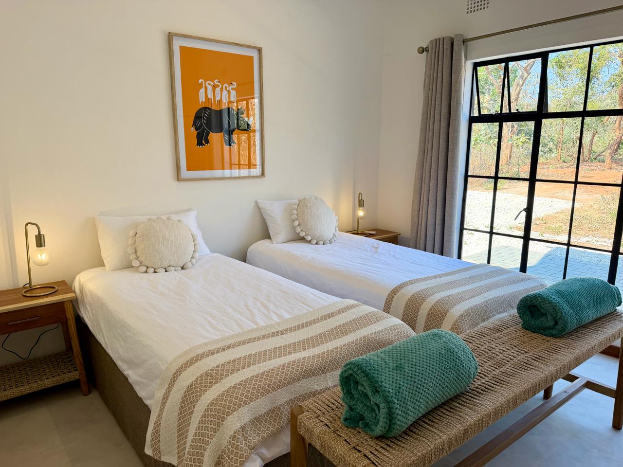 The twin bedroom, with white linen, a wooden bench and a door to the garden